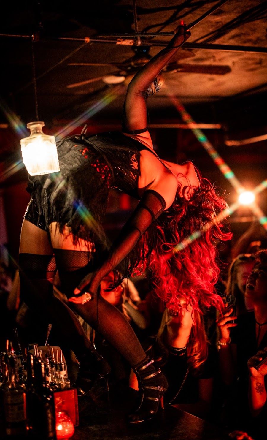 Burlesque performer in dramatic backbend under crimson stage lights
